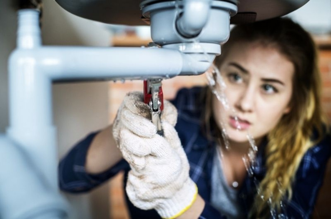 A plumber girl fixing water pipe